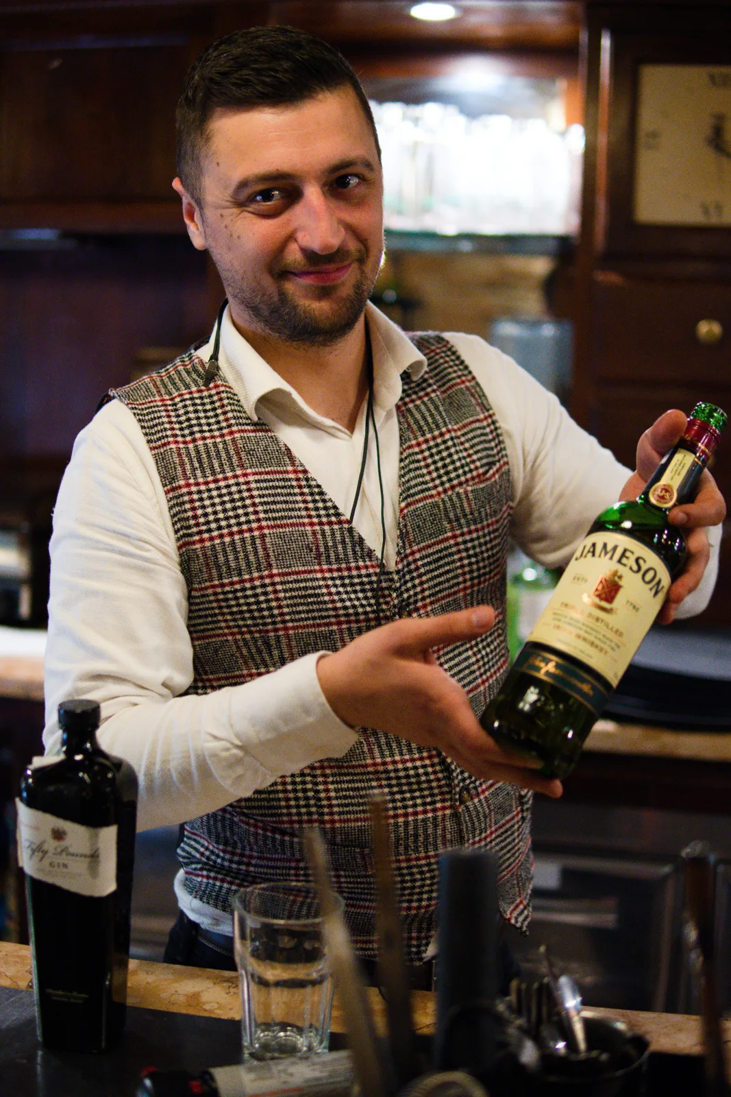 Barman ritratto dietro il banco con una bottiglia in mano