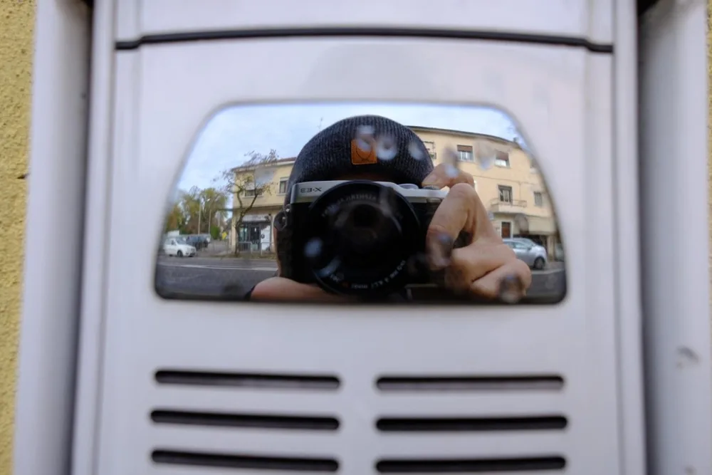 Autoritratto di un fotografo riflesso con la macchina fotografica in uno specchio urbano